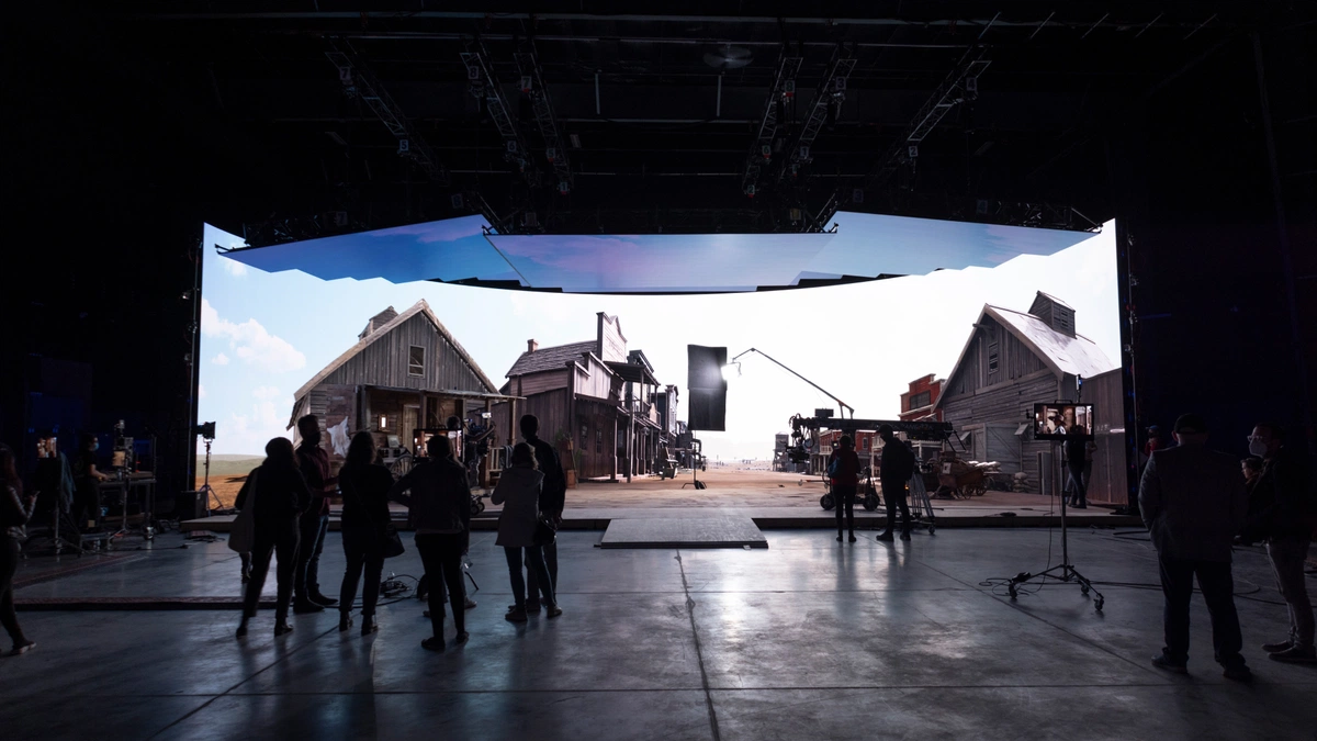 Virtual production crew in front of LED volume displaying a virtual town
