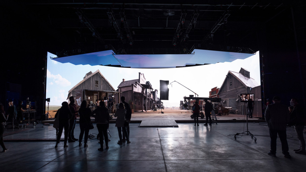 Virtual production crew in front of LED volume displaying a virtual town
