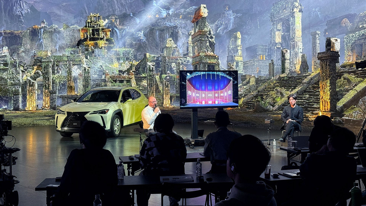 A real car, two men, and a TV set sit in front of a virtual set of ancient ruins