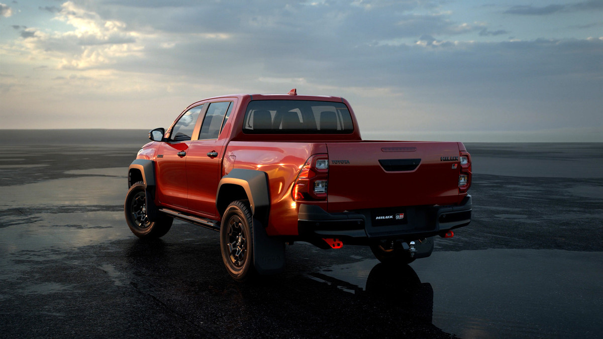 A red Toyota pickup truck on a plain at golden hour.