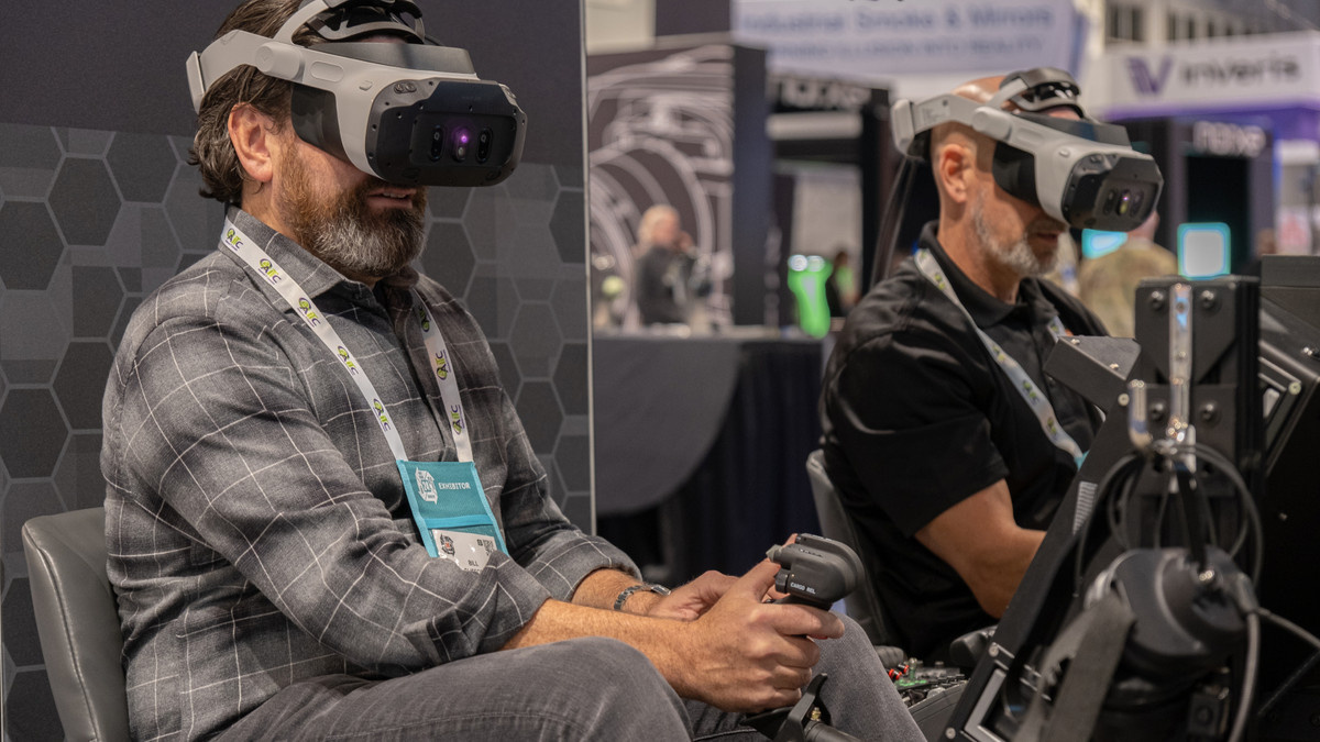 I/ITSEC attendees wearing VR headsets try out a simulator.