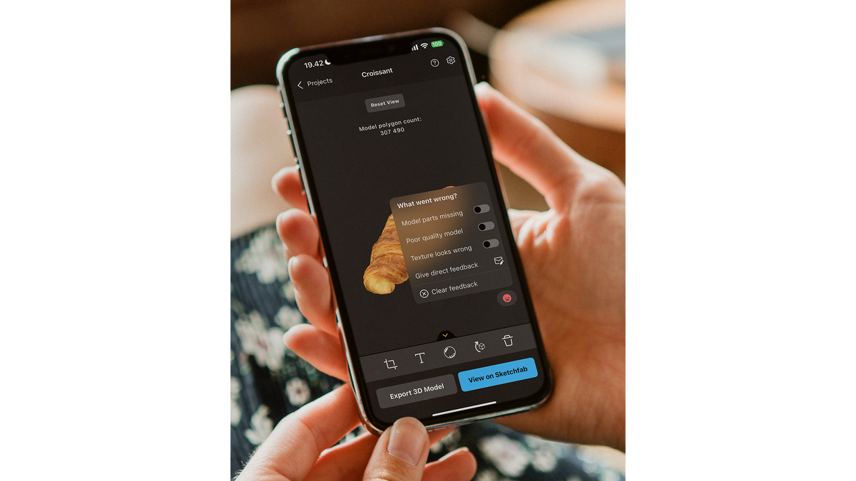 Hands holding a cell phone with a scanned image of bread and RealityScan user interface.
